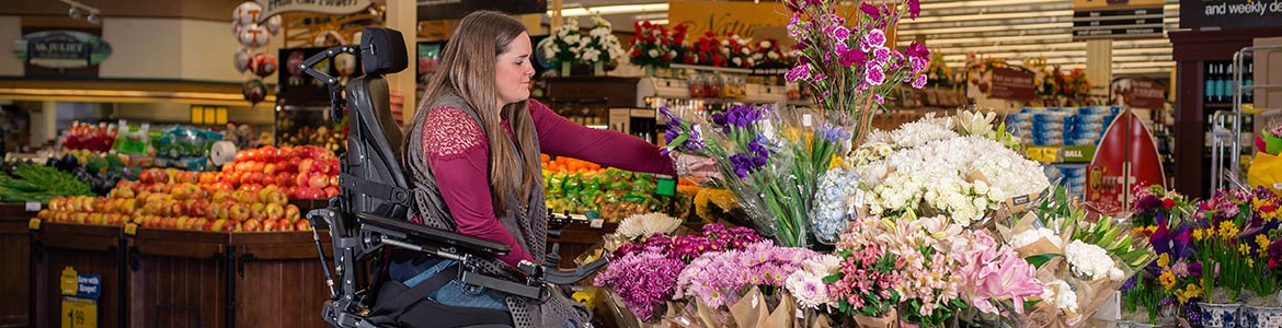Girl in a wheelchair looking at flowers in a grocery store.